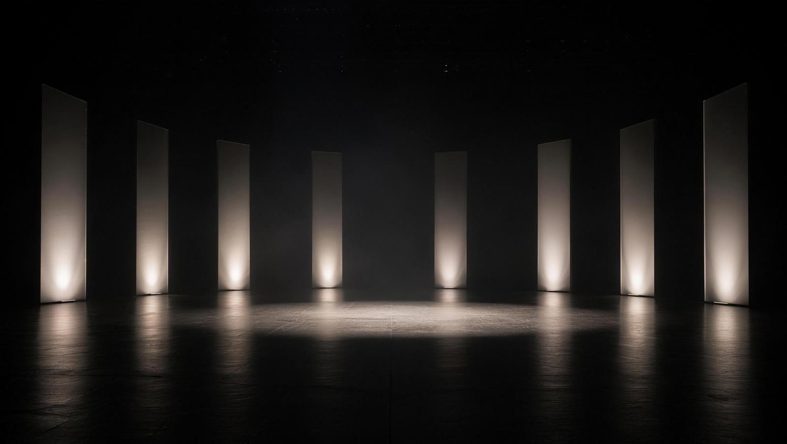 Minimal dark stage with a semicircle of tall illuminated panels